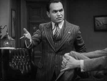 Movie still from “Little Caesar” (1931), directed by Mervyn LeRoy – An old photo of a man in a suit and tie; Medium shot, Over the shoulder angle