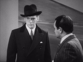 Movie still from “Little Caesar” (1931), directed by Mervyn LeRoy – A man wearing a hat and a suit and tie; Medium shot, Over the shoulder angle