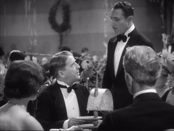 Movie still from “Little Caesar” (1931), directed by Mervyn LeRoy – Two men in tuxedos are talking to each other; Medium shot, Over the shoulder angle