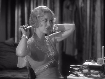 Movie still from “Little Caesar” (1931), directed by Mervyn LeRoy – A black - and - white photo of a woman holding her hair; Medium shot, Over the shoulder angle