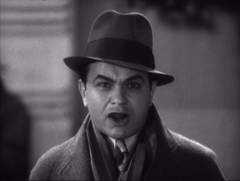 Movie still from “Little Caesar” (1931), directed by Mervyn LeRoy – A man wearing a hat and a coat and a scarf; Close Up shot, High angle