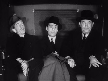 Movie still from “Little Caesar” (1931), directed by Mervyn LeRoy – A group of men sitting next to each other on a bench; Medium shot, Low angle