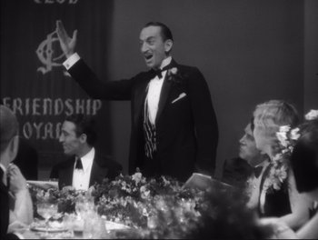 Movie still from “Little Caesar” (1931), directed by Mervyn LeRoy – A black and white photo of a man in a tuxedo at a table; Medium shot, Low angle