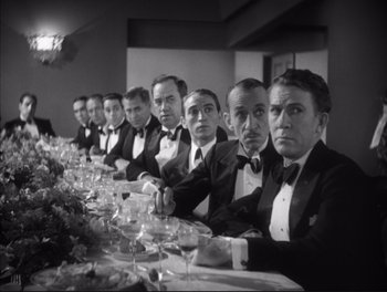 Movie still from “Little Caesar” (1931), directed by Mervyn LeRoy – A black and white photo of men sitting at a long table; Medium shot, High angle