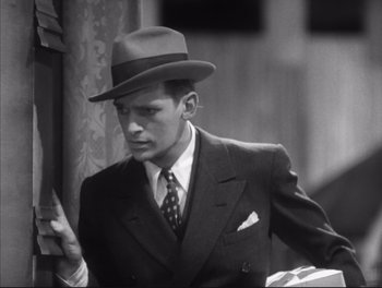 Movie still from “Little Caesar” (1931), directed by Mervyn LeRoy – A black and white photo of a man in a suit and hat; Close Up shot, Low angle