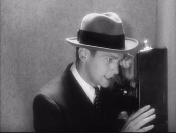 Movie still from “Little Caesar” (1931), directed by Mervyn LeRoy – A man in a suit and a hat looking in a mirror; Close Up shot, Low angle