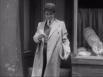 Movie still from “Little Caesar” (1931), directed by Mervyn LeRoy – A black and white photo of a man wearing a hat and a coat; Medium shot, Low angle