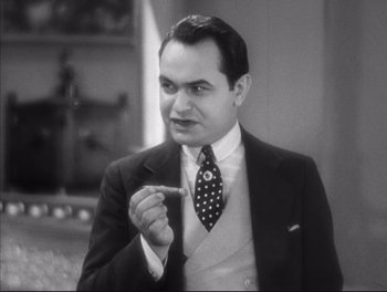 Movie still from “Little Caesar” (1931), directed by Mervyn LeRoy – A man in a suit and tie pointing to his ear; Close Up shot, High angle
