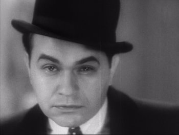 Movie still from “Little Caesar” (1931), directed by Mervyn LeRoy – A man wearing a top hat and a suit; Close Up shot, Low angle