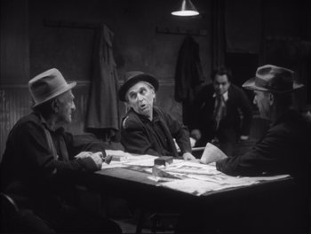 Movie still from “Little Caesar” (1931), directed by Mervyn LeRoy – A black and white photo of a group of men sitting at a table; Medium shot, Over the shoulder angle