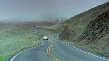 Movie still from “Little Dieter Needs to Fly” (1997), directed by Werner Herzog – A car driving down a curvy road on a cloudy day; Extreme Wide shot, High angle