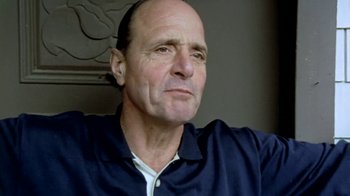 Movie still from “Little Dieter Needs to Fly” (1997), directed by Werner Herzog – An older bald man with a goatee looking at the camera; Close Up shot, Low angle