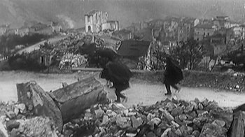 Movie still from “Little Dieter Needs to Fly” (1997), directed by Werner Herzog – A black and white photo of people walking through rubble; Wide shot, High angle
