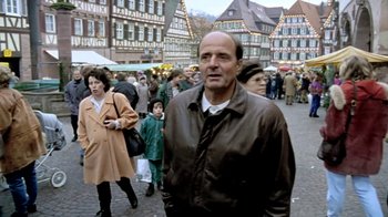 Movie still from “Little Dieter Needs to Fly” (1997), directed by Werner Herzog – A man standing in the middle of a crowd of people; Medium shot, Over the shoulder angle