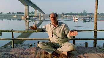 Movie still from “Little Dieter Needs to Fly” (1997), directed by Werner Herzog – A man sitting on a pier in front of a body of water; Medium shot, Low angle