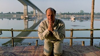 Movie still from “Little Dieter Needs to Fly” (1997), directed by Werner Herzog – A man kneeling down in front of a body of water; Medium shot, Low angle