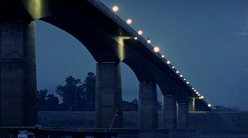 Movie still from “Little Dieter Needs to Fly” (1997), directed by Werner Herzog – A bridge that is lit up at night time; Extreme Wide shot, Low angle