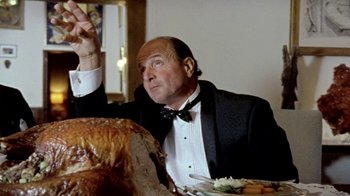 Movie still from “Little Dieter Needs to Fly” (1997), directed by Werner Herzog – A man sitting at a dinner table with a turkey; Medium shot, Low angle