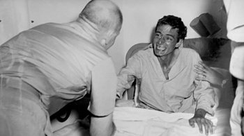 Movie still from “Little Dieter Needs to Fly” (1997), directed by Werner Herzog – Two men sitting at a table and shaking hands; Medium shot, Overhead angle