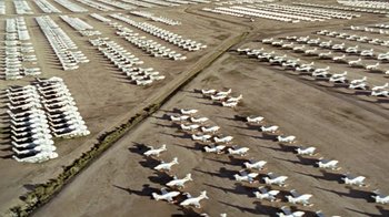 Movie still from “Little Dieter Needs to Fly” (1997), directed by Werner Herzog – An aerial view of many white planes parked in a field; Extreme Wide shot, High angle