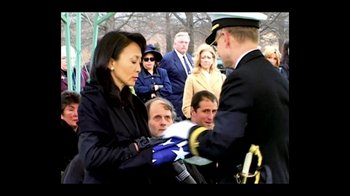 Movie still from “Little Dieter Needs to Fly” (1997), directed by Werner Herzog – A man in a military uniform handing a flag to a woman; Medium shot, High angle