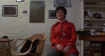 Movie still from “Little Murders” (1971), directed by Alan Arkin – A woman in a red coat sitting in a room; Medium shot, Low angle