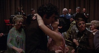 Movie still from “Little Murders” (1971), directed by Alan Arkin – A man and a woman kissing in front of a crowd; Medium shot, High angle