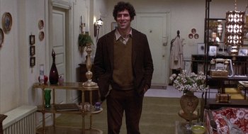 Movie still from “Little Murders” (1971), directed by Alan Arkin – A man standing in a living room wearing a brown suit; Medium shot, Low angle
