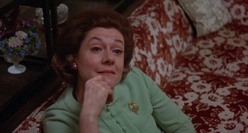 Movie still from “Little Murders” (1971), directed by Alan Arkin – An older woman sitting on a couch with her hand on her chin; Close Up shot, Over the shoulder angle