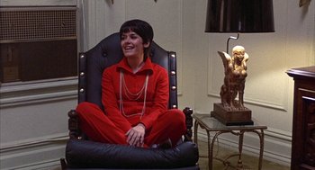 Movie still from “Little Murders” (1971), directed by Alan Arkin – A woman sitting in a chair in a room; Medium shot, High angle