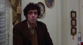 Movie still from “Little Murders” (1971), directed by Alan Arkin – A man in a brown jacket sitting in front of a white wall; Close Up shot, Over the shoulder angle