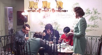 Movie still from “Little Murders” (1971), directed by Alan Arkin – A group of people sitting around a table eating; Medium shot, High angle