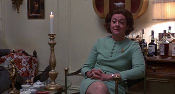Movie still from “Little Murders” (1971), directed by Alan Arkin – A woman sitting in a chair in front of a lit candle; Medium shot, Over the shoulder angle