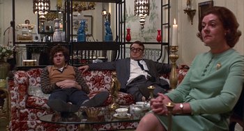 Movie still from “Little Murders” (1971), directed by Alan Arkin – Two men and a woman sitting on a red couch; Medium shot, High angle