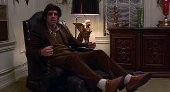 Movie still from “Little Murders” (1971), directed by Alan Arkin – A man sitting in a chair in a living room; Medium shot, Low angle
