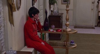 Movie still from “Little Murders” (1971), directed by Alan Arkin – A person sitting on a bench in a living room; Medium shot, High angle