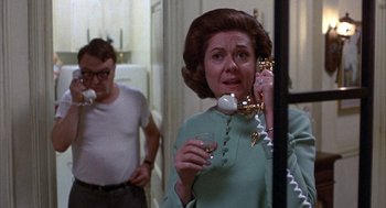 Movie still from “Little Murders” (1971), directed by Alan Arkin – An older woman talking on a phone while holding a wine glass; Medium shot, Over the shoulder angle