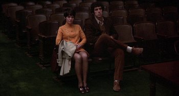 Movie still from “Little Murders” (1971), directed by Alan Arkin – A man and a woman sitting in a row of seats; Wide shot, High angle