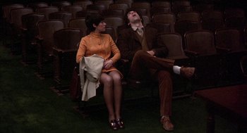 Movie still from “Little Murders” (1971), directed by Alan Arkin – A man and a woman sitting in a row of seats; Wide shot, High angle