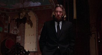 Movie still from “Little Murders” (1971), directed by Alan Arkin – A man with long hair and a beard wearing a suit and tie; Medium shot, Low angle