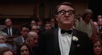 Movie still from “Little Murders” (1971), directed by Alan Arkin – A man in a tuxedo standing in front of a crowd; Close Up shot, Low angle