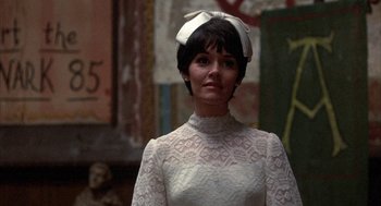 Movie still from “Little Murders” (1971), directed by Alan Arkin – A woman in a white dress with a bow on top of her head; Close Up shot, Low angle