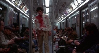 Movie still from “Little Murders” (1971), directed by Alan Arkin – A man with blood all over his shirt on a subway train; Wide shot, Low angle