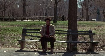 Movie still from “Little Murders” (1971), directed by Alan Arkin – A man sitting on top of a wooden bench in a park; Wide shot, High angle