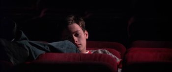 Movie still from “Little Odessa” (1994), directed by James Gray – A young man is sleeping on a red couch; Medium shot, High angle