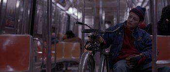 Movie still from “Little Odessa” (1994), directed by James Gray – A person riding a bike on a city street; Medium shot, High angle