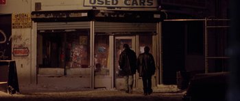 Movie still from “Little Odessa” (1994), directed by James Gray – Two people walking in front of a used cars store; Wide shot, Low angle