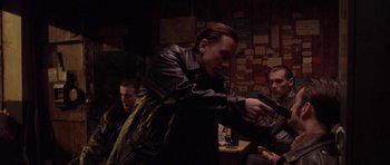 Movie still from “Little Odessa” (1994), directed by James Gray – A man in a leather jacket holding a handgun; Medium shot, Over the shoulder angle