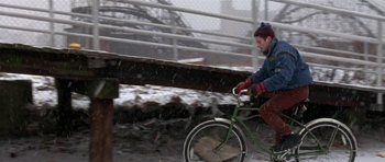 Movie still from “Little Odessa” (1994), directed by James Gray – A person riding a bike on a bridge in the snow; Wide shot, High angle