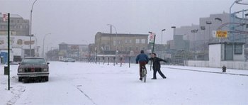 Movie still from “Little Odessa” (1994), directed by James Gray – Two people walking and a bike in the snow; Extreme Wide shot, Over the shoulder angle